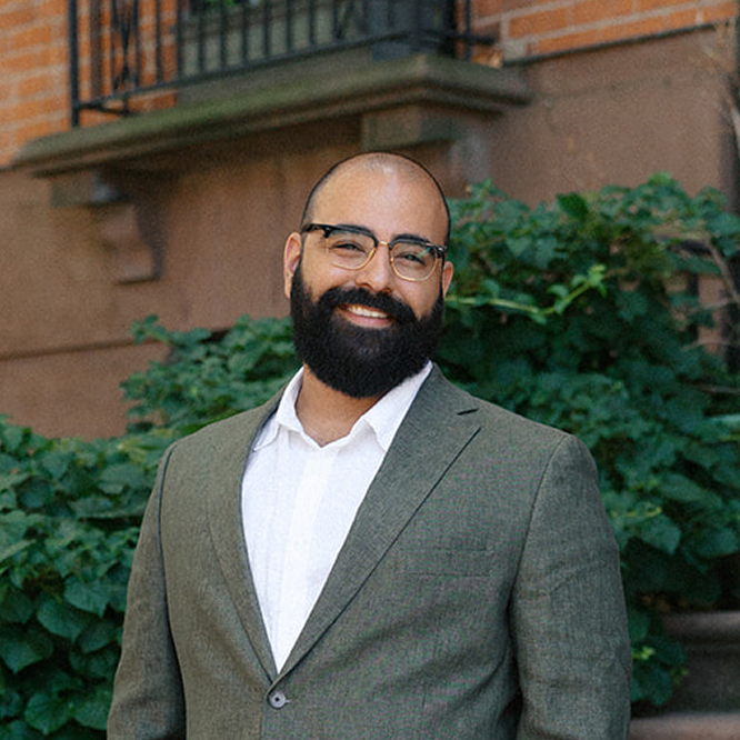 An image of an extraordinarily handsome and capable man, whose face inspires feelings of confidence and reliability. Daunish, standing on the streets of Brooklyn.